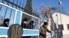 Ukraine - A Ukrainian soldier (R) leaves his base as members of the Russian Navy look on in Sevastopol March 21, 2014. 