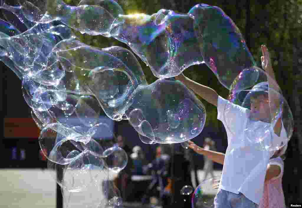 Children play with soap bubbles made by a busker on the South Bank in London. (Reuters/Andrew Winning)