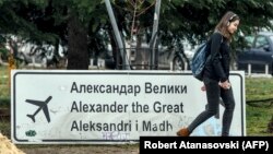 Një vajzë kalon pranë shenjës ku shkruan “Aleksandri i Madh”, në aeroportin ë Shkup. 19 shkurt, 2018