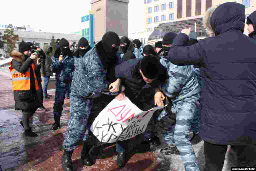 Спецназ забирает человека, в руках которого плакат с надписью: «Дулат — жертва системы».