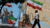 An Iranian man walks next to a mural on a street in Tehran on May 11.