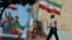 An Iranian man walks next to a mural on a street in Tehran on May 11.