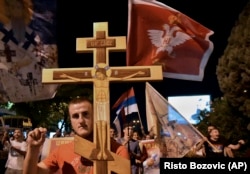 An opposition supporter holds a cross during a church-led protest in Podgorica on August 27.