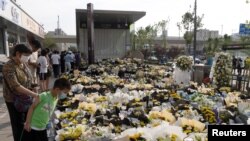 Oamenii plasează flori în memoria victimelor ce au murit înecate ca urmare a inundării magistralei 5 din Zhengzhou, China, 27 iulie 2021. Inundația liniei de metrou a fost provocată de precipitațiile abundente ce au lovit provincia chineză Henan.