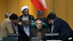 Iranian parliament speaker Ali Larijani, seated at center, talks with a group of lawmakers in a session of parliament to debate proposed cabinet by President Hassan Rouhani, in Tehran, Iran, Thursday, Aug. 17, 2017. (AP Photo/Vahid Salemi)