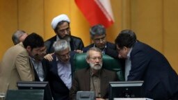 Iranian parliament speaker Ali Larijani, seated at center, talks with a group of lawmakers in a session of parliament to debate the proposed cabinet by President Hassan Rouhani, in Tehran, Iran, Thursday, Aug. 17, 2017.