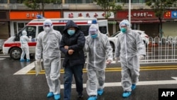 China -- Medical staff members wear protective clothing to help stop the spread of a deadly virus accompanying a patient as they walk into a hospital in Wuhan, January 26, 2020.