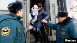 Russian Emergencies Ministry workers help a woman with a child out of a train as refugees from eastern Ukraine arrive at a railway station in the southern city of Stavropol on February 24.