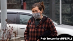 Көше бойында медициналық маска киіп келе жатқан әйел. Алматы, 18 наурыз 2020 жыл.