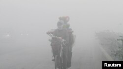 A man rides a bicycle loaded with sundries on a smoggy morning in Lahore, Pakistan.