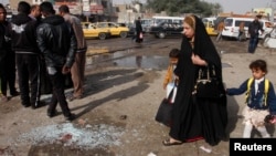 Жінка з дитиною йдуть повз місце вибуху в Багдаді, 9 лютого 2015 року