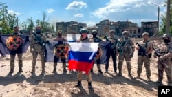 In a grab taken from video and released by Prigozhin Press Service on May 20, Yevgeny Prigozhin, head of the Wagner mercenary group, holds a Russian flag in front of his soldiers in Bakhmut, Ukraine. 