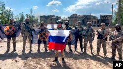 Evgheni Prigojin, șeful mercenarilor Wagner, ține în mână un steag rusesc în fața soldaților săi, Bahmut, Ucraina, 20 mai 2023.