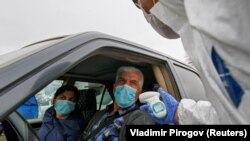 Посгоҳе дар Бишкек. Ходими тиббӣ ҳарорати мусофирони мошинеро месанҷанд
