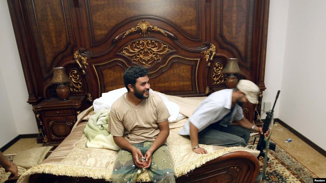 Rebel fighters sit on a bed at embattled Libyan leader Muammar Gaddafi's farm house near the town of Abu Grein on the way to Sirte, August 30.
