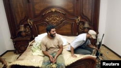 Rebel fighters sit on a bed at embattled Libyan leader Muammar Gaddafi's farm house near the town of Abu Grein on the way to Sirte, August 30.