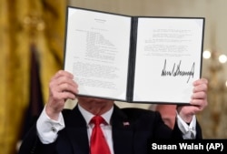 Trump shows off a "Space Policy Directive" after signing it during a meeting of the National Space Council in the East Room of the White House on June 18.