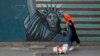 IRAN -- A woman walks her dog past a satirical drawing of Statue of Liberty on the wall of the former U.S. Embassy in Tehran, May. 8, 2018