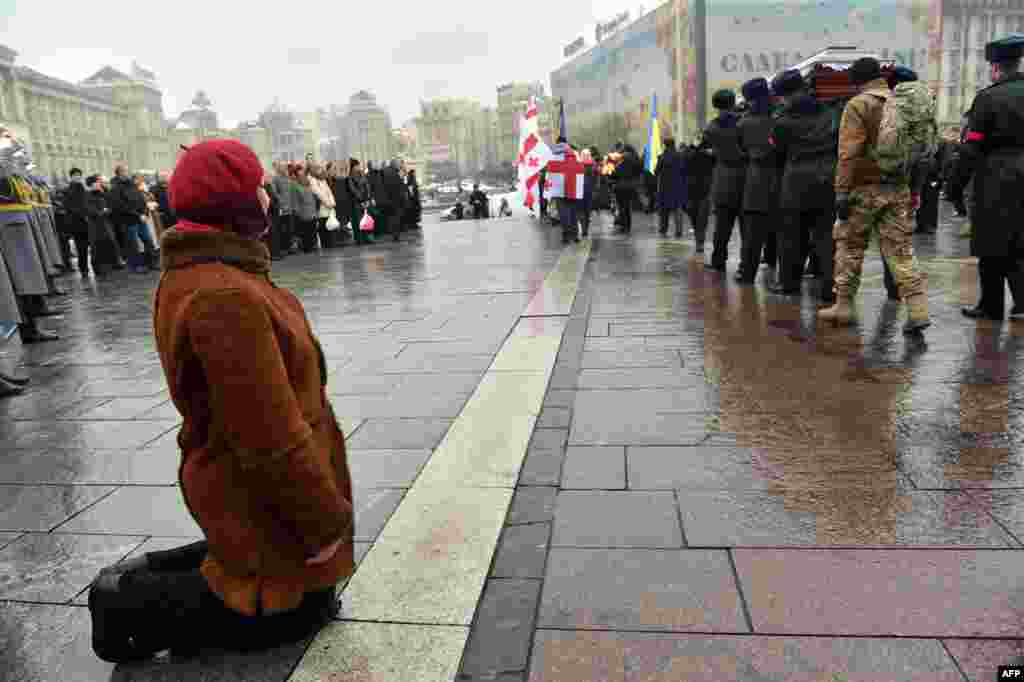A woman kneels as Ukrainian servicemen carry the coffin of Tomaz Sukhiashvili, a Georgian fighter of the Ukrainian volunteer battalion of Donbas who died during fighting against pro-Russian rebels, on Independence Square in Kyiv. (AFP/Sergei Supinsky)