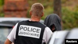 Pjesëtari i policisë duke e ndalur një person gjatë hetimeve pas sulmit në kishë në rajonin Normandi në Francë