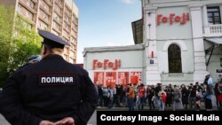 Полицейский на фоне театра «Гоголь-центр» и его посетителей в Москве.