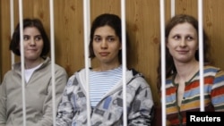 Yekaterina Samutsevich (left), Nadezhda Tolokonnikova (center), and Maria Alekhina behind bars before a court hearing in Moscow on July 20.
