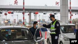 Un polițist îi măsoară temperatura unui șofer în Wuhan. 24 ianuarie 2020