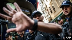 Turkish anti-riot police officers push away journalists and photographers during a rally in June.