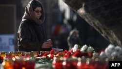A woman places a candle at a memorial to the victims of Soviet-era political repression.