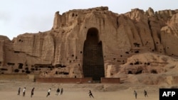 Afghan boys play soccer in front of the empty seat of one of two Buddha statues destroyed by the Taliban in 2001 in Bamiyan Province.