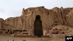 Children play soccer in front of the empty seat of one of two Buddha statues in Bamiyan province, which was destroyed by the Taliban in 2001.