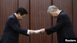 Yotaro Hatamura (right), a University of Tokyo engineering professor and the head of a government-appointed panel investigating the cause of the Fukushima nuclear crisis, hands over the final report to Japan's Prime Minister Yoshihiko Noda in Tokyo.