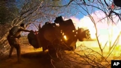 A Russian soldier fires a gun toward a Ukrainian position in the Russian-Ukrainian border area in the Kursk region.