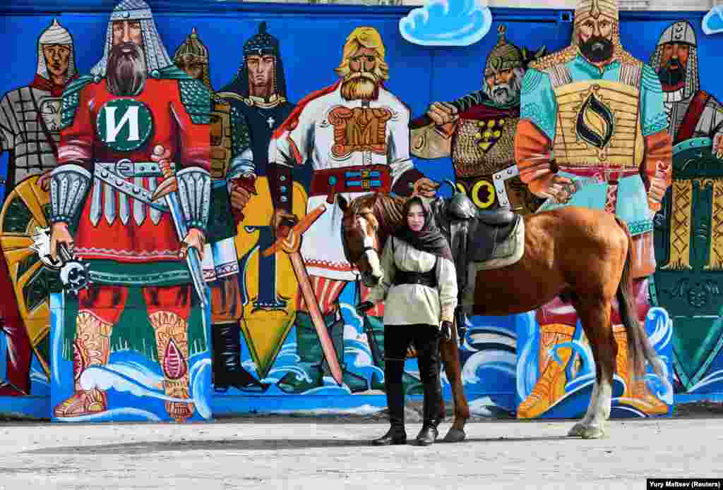 A Russian woman stands with a horse next to graffiti during celebrations of the Defender of the Fatherland Day in Vladivostok on February 23. (Reuters/Yuri Maltsev)