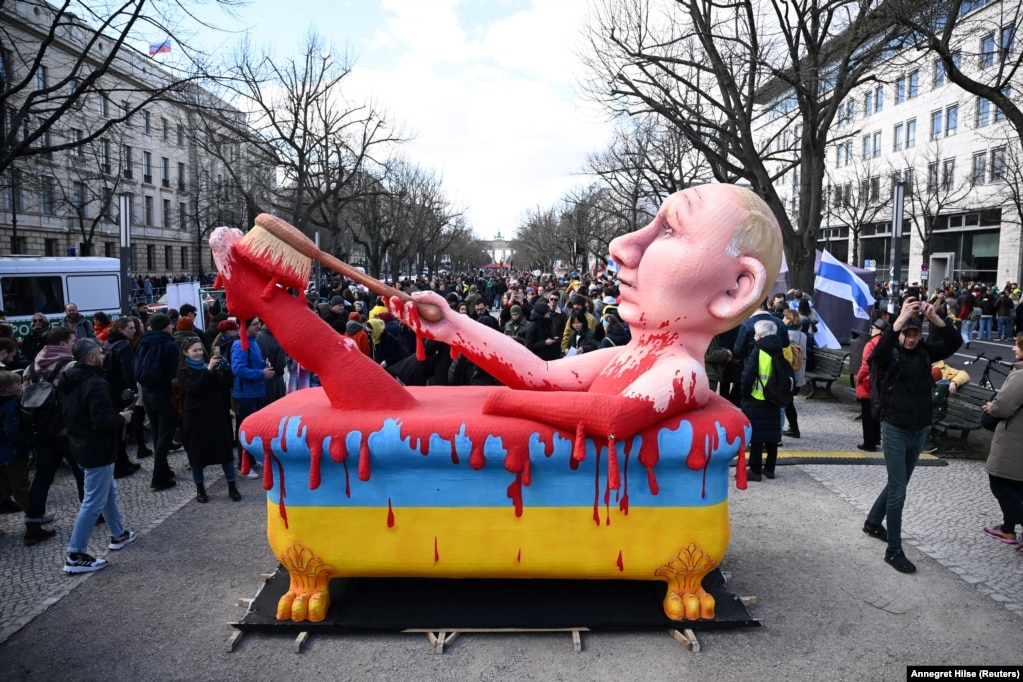 Një imazh i Putinit duke u larë në gjakun ukrainas përpara ambasadës ruse në Berlin në mars 2024.