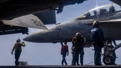 US sailors prepare to taxi a fighter jet on the flight deck of the USS Abraham Lincoln aircraft carrier in the Middle East. 