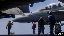 US sailors prepare to taxi a fighter jet on the flight deck of the USS Abraham Lincoln aircraft carrier in the Middle East. 