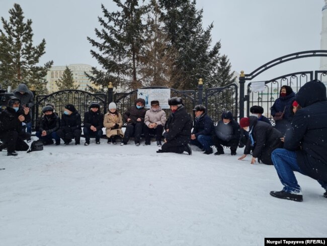 Люди у закрытой мечети читают коран.