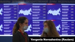 People speak near electronic information screens at the headquarters of Russia's Central Election Commission in Moscow during the three-day parliamentary election (September 17, 2021)
