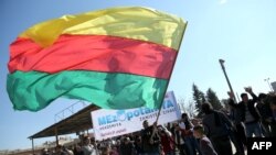 Një kurd në Siri, duke valvitur flamurin e krahut politik, YPG, gjatë një proteste