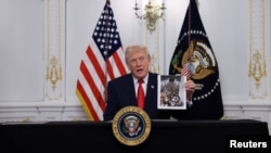 ترامپ با عکسی در دست دارد که به‌گفتهٔ او مربوط به یک هواپیمای پناهجویان افغان است