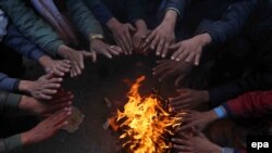 FILE: Afghan people gather around a fire to beat the cold as winter season approaches.