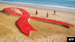 File photo of women walking past a 100 foot long AIDS red ribbon sand sculpture.