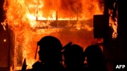 A shop burns as riot police try to regain control of the streets in Tottenham