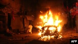 A Pakistani man runs past a burning vehicle after a suicide-bomb attack on an election campaign rally in Peshawar on April 16.