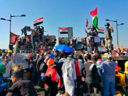 Anti-government protesters control some barriers set by Iraqi security forces to close the bridge leading to the Green Zone during ongoing protests in Baghdad, Iraq, Friday, Nov. 1, 2019. (AP Photo/Khalid Mohammed)