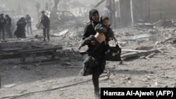 A Syrian woman holds a child and runs for cover following government air strikes on the rebel-held enclave of Douma late last month.
