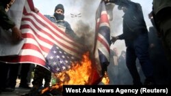 Demonstrators burn the U.S. and British flags during a protest in Tehran after the killing of General Soleimani.