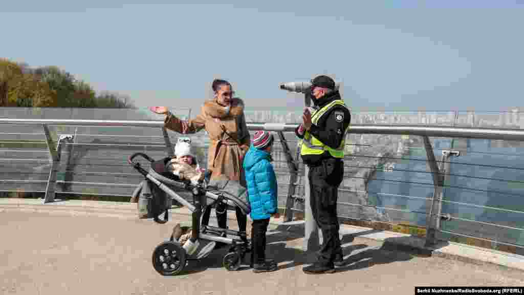 Працівники поліції патрулюють Пішохідно-велосипедний міст через Володимирський узвіз і в разі необхідності вдаються до усних попереджень громадян, які порушують постанову Кабінету міністрів України (КМУ). Київ, 7 квітня 2020 року