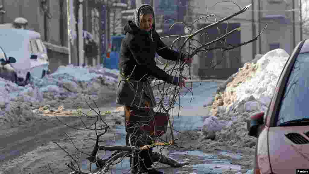 A woman carries firewood on a street in Bucharest, Romania.